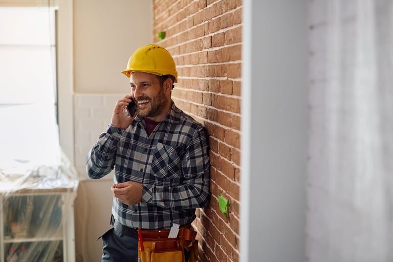 Happy construction worker taking a customer call on a job site